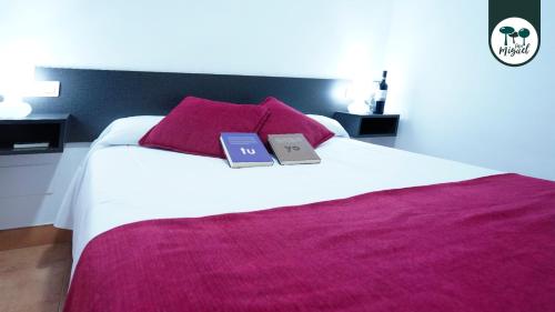 a bedroom with a white bed with two books on it at Hostal Rte. Casa Miguel in Matalascañas