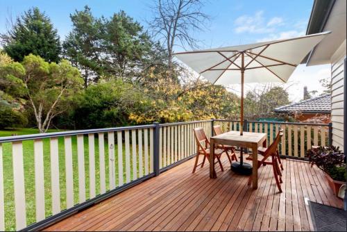 a wooden deck with a table and an umbrella at Korla Cottage, Leura Family & Pet Friendly Stay in Leura