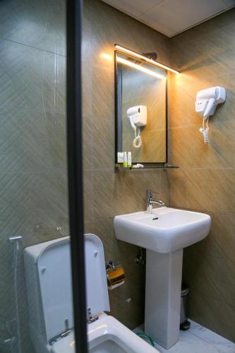 a bathroom with a sink and a toilet and a mirror at Al Sharq Hotel in Sharjah