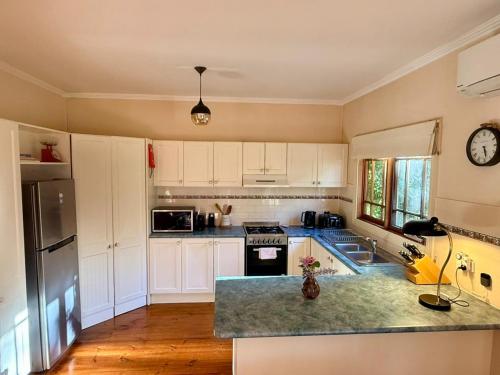a kitchen with white cabinets and a counter top at Korla Cottage, Leura Family & Pet Friendly Stay in Leura