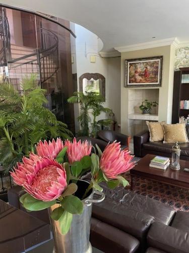 a vase with pink flowers in a living room at Casa Flora Guesthouse in Pretoria