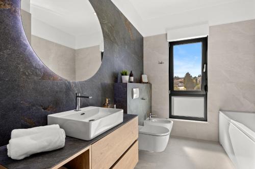 a bathroom with a sink and a toilet and a mirror at Luxury Villa del Sol in Premantura
