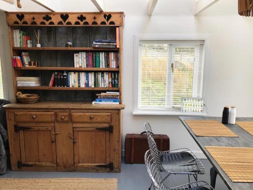 a room with a book shelf and a table and chairs at Raven Cottage in Rhiconich