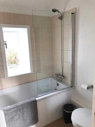 a bathroom with a bath tub and a window at Raven Cottage in Rhiconich