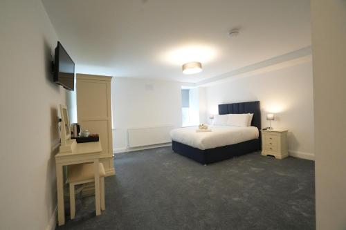 a bedroom with a bed and a desk and a television at The Lodge in Dunmore