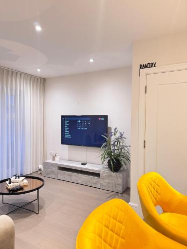a living room with a tv and a yellow chair at Spacious 4-Bedroom House Ideal for Contractors, Families & Business Stays in Reading, Offers 3 Parkings in Burghfield
