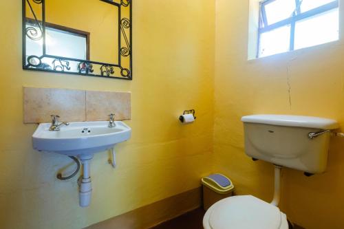 Un baño con lavabo, inodoro y espejo. en Jameson House, en Karatu