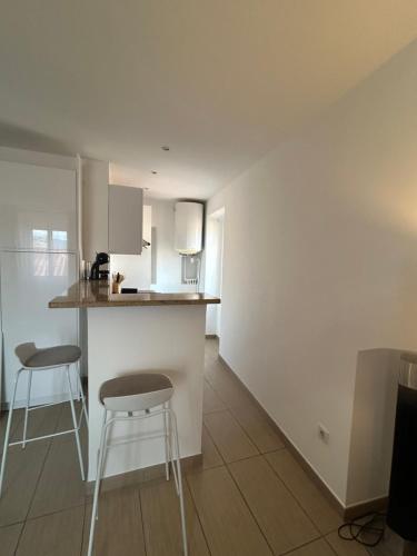 a kitchen with two bar stools and a counter at Studio centre ville in Ajaccio