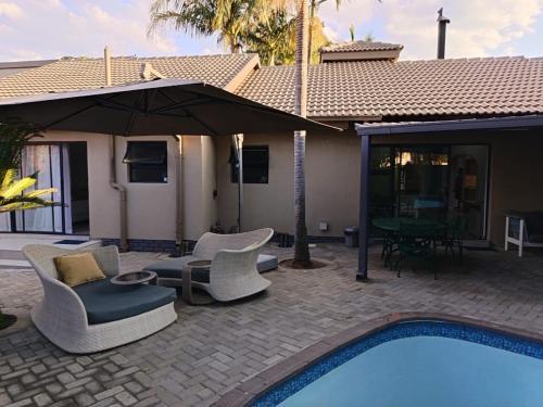 a patio with chairs and an umbrella next to a pool at Lady Daisy Boutique Guesthouse in Rustenburg