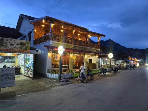 a man riding a motorcycle in front of a building at Sokmixay Backpackers hostel in Nongkhiaw