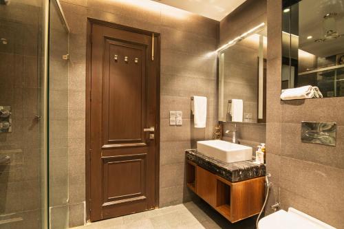 a bathroom with a sink and a wooden door at Luxury HomeStay Prime Location, South Delhi in New Delhi