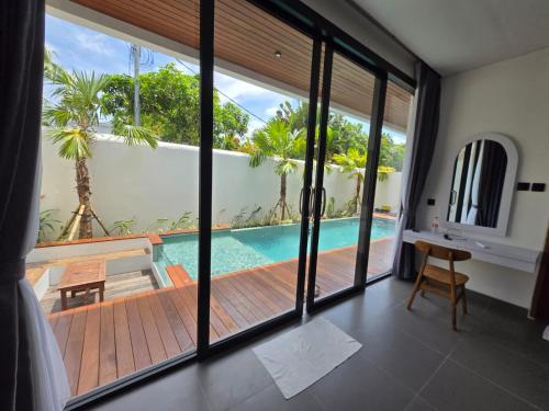 a room with a view of a swimming pool through a sliding glass door at Serenity Nirvana Palace- Pool, Kichen, Deluxe & Dorm Rooms Near Uluwatu in Jimbaran