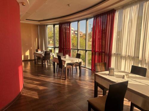 a restaurant with tables and chairs and large windows at Nork Residence Hotel in Yerevan