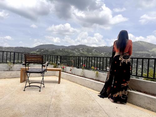 a woman standing on a balcony looking at the mountains at SereneVbes - Kandy in Kandy