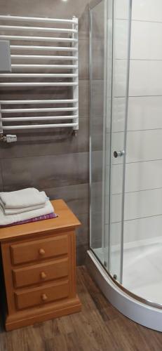 a bathroom with a shower with a wooden dresser and a wooden table at Cichy Zaułek 6A in Brodnica