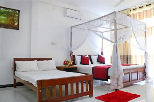a bedroom with two beds and a canopy bed at Unaway Holiday Home in Unawatuna