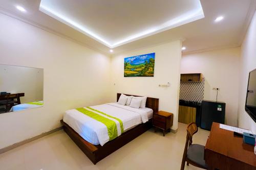 a bedroom with a bed and a desk and a television at Mora Residence in Jimbaran