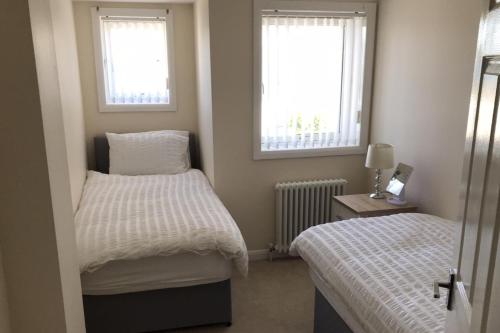 a small bedroom with two beds and two windows at Beautiful 3-Bed Apartment in Gourock in Gourock
