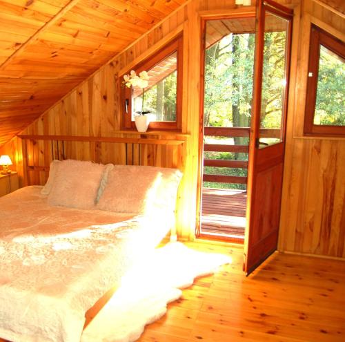 a bedroom with a bed in a wooden cabin at Domek Zofiówka dostęp na kod in Zofiówka