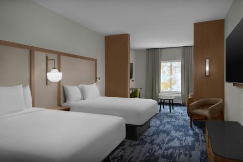 a hotel room with two beds and a desk at Fairfield Inn & Suites Weldon in Weldon