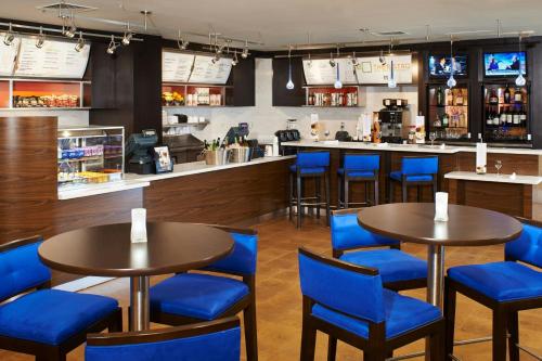 オーバーランド・パークにあるCourtyard Kansas City Overland Park / Convention Centerのテーブル2台と青い椅子が備わるレストラン