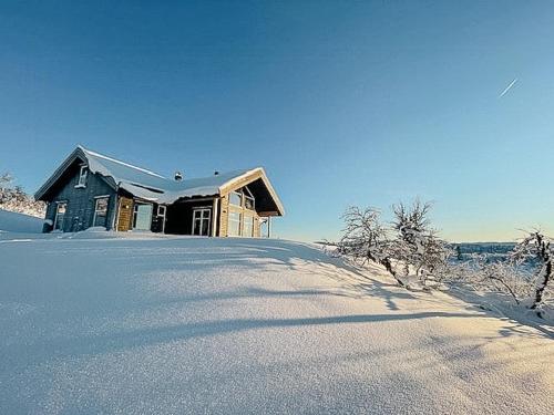 a wooden house in the snow with a snow covered yard at Modern Cabin With Views Of Langsua National Park in Steinsetbygdi