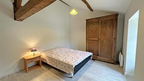 a bedroom with a bed and a wooden cabinet at Gîte Les Champs N°3 in Saint-Mathieu