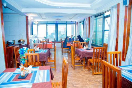 KasuluBWAMI DUBAI HOTEL KASULU的一间设有桌椅的餐厅,以及坐在里面的人