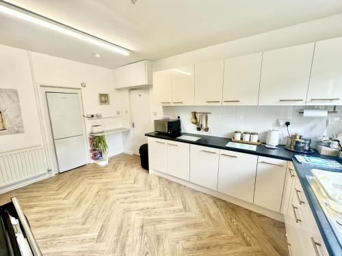 cocina con armarios blancos y suelo de madera en Secluded Hot Tub, With Views - Abergavenny, en Abergavenny