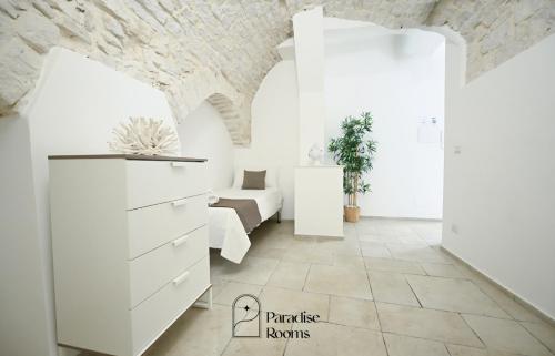 a bedroom with white furniture and a brick wall at Paradise Rooms in Bitritto