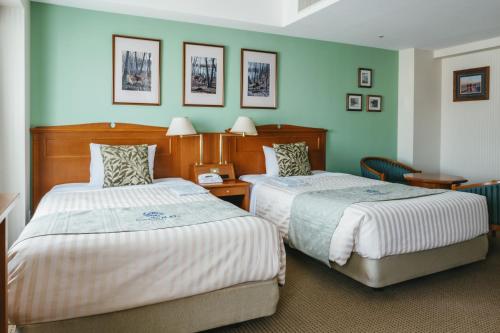 two beds in a room with green walls at Hotel Boston Plaza Kusatsu in Kusatsu