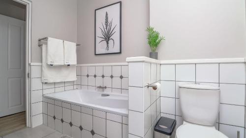 a white bathroom with a tub and a toilet at La Vita Alti in Mossel Bay