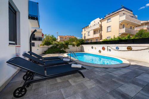 a swimming pool with two lounge chairs next to a building at Villa Essenza Rossa in Vodice only 650 meters from the beach in Vodice