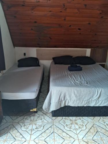a bedroom with two beds and a wooden ceiling at Chale Rio Nascente in Salesópolis