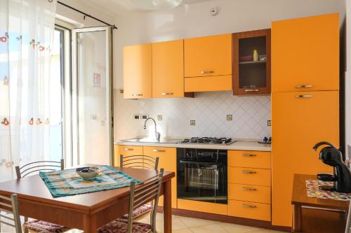 a kitchen with orange cabinets and a table and a dining room at La Perla di Ponente in Milazzo