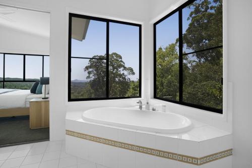 baño con bañera, cama y ventanas en Dale View Retreat at Mapleton, en Flaxton