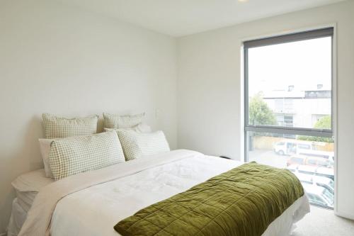une chambre blanche avec un lit et une grande fenêtre dans l'établissement Spacious 3 Bedroom Townhouse Steps from the CBD, à Linwood