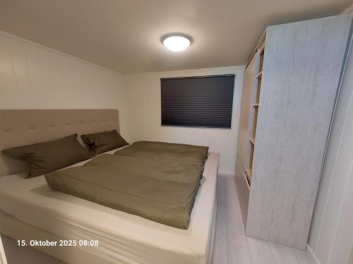 a small bedroom with a bed and a window at Nordlys Apartment in Hamnvik