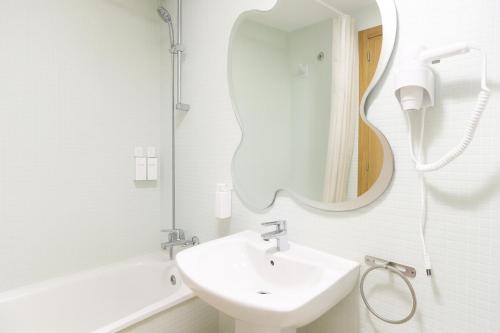 a white bathroom with a sink and a mirror at Tu refugio en Canet, piscina, parking y playa in Canet de Berenguer