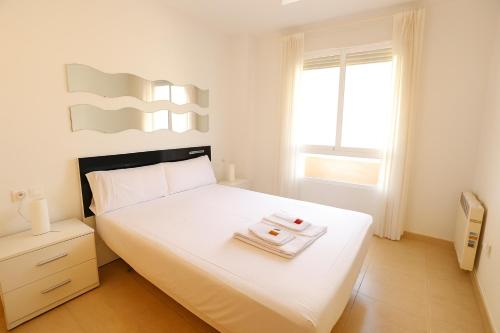a bedroom with a white bed with two trays on it at Tu refugio en Canet, piscina, parking y playa in Canet de Berenguer