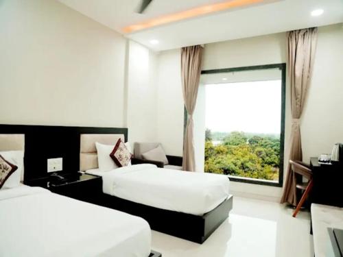 two beds in a hotel room with a window at The Aanandam Hotel Resort in Itārsi