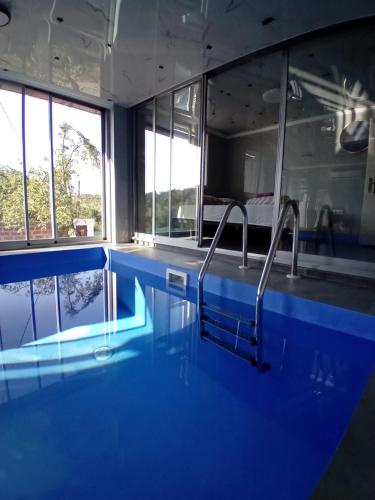 a swimming pool in a room with blue walls and windows at Gyps Vikendica with Swimming Pool and Sauna in Tuzla