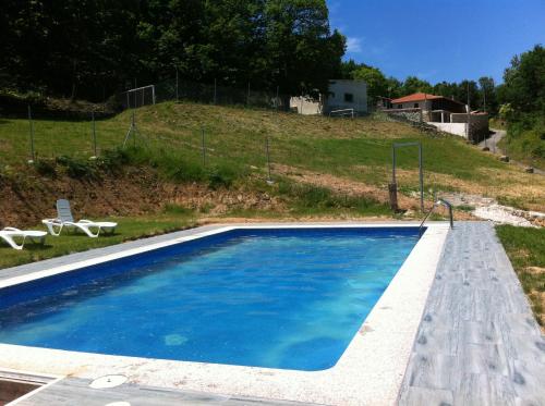 a blue swimming pool with a hill in the background at Complejo rural Aira Sacra in Vilamelle