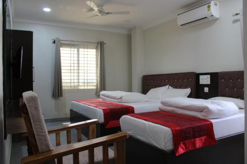 a room with three beds and a table and a window at SRG Shivam Residency in Tiruvannāmalai