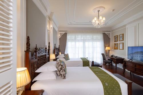 a hotel room with two beds and a television at Ping Pura Riverside Resort & Spa Chiang Mai in Chiang Mai