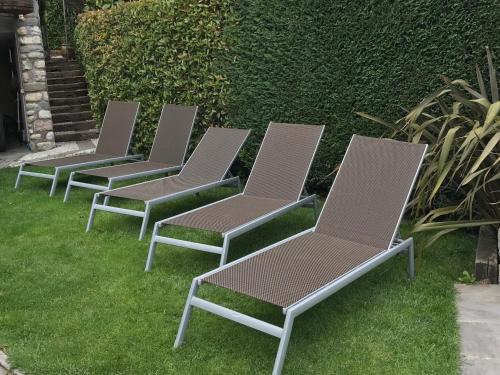 a row of lawn chairs sitting in the grass at Bed and Breakfast Casa del Nonno in Adrara San Martino