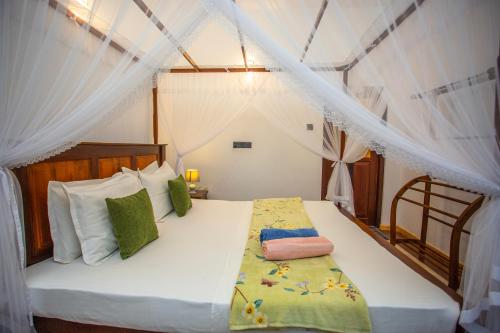 a bedroom with a bed with white drapes at Saku Residence in Unawatuna