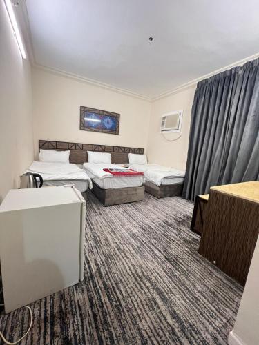 a hotel room with two beds and a couch at نزل الزائر 2 in Al Madinah