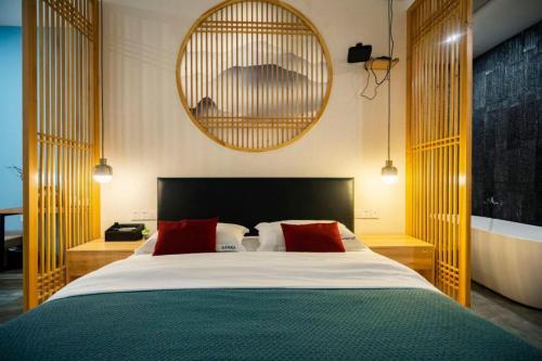 a bedroom with a large bed with two red pillows at Heinemann Hotel standard king room Building A with a jacuzzi and a local in Baoguosi