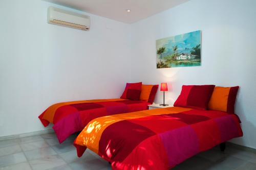 2 camas en una habitación con rojo y naranja en El Nido, en Almuñécar